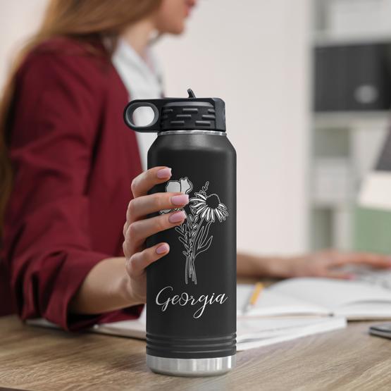 Custom Engraved 32 oz Black Water Bottle on Woman’s Desk while she works on a computer.