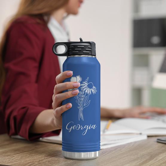 Custom Engraved 32 oz Blue Water Bottle on Woman’s Desk while she works on a computer.