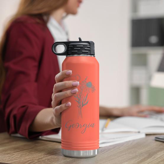 Custom Engraved 32 oz Coral Water Bottle on Woman’s Desk while she works on a computer.