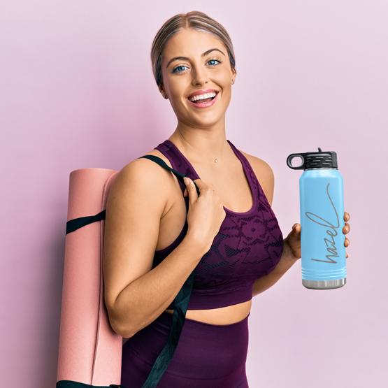 Custom Engraved 32 oz Light Blue Water Bottle held by a happy woman with a sample engraving for Hazel