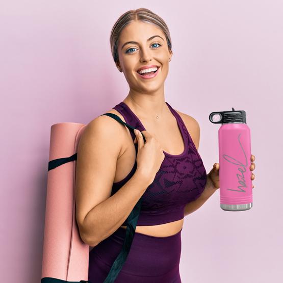 Custom Engraved 32 oz Pink Water Bottle held by a happy woman with a sample engraving for Hazel