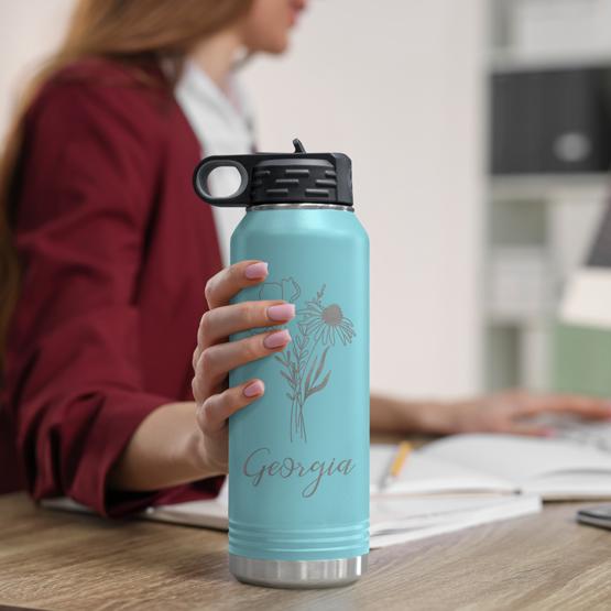 Custom Engraved 32 oz Teal Water Bottle on Woman’s Desk while she works on a computer.