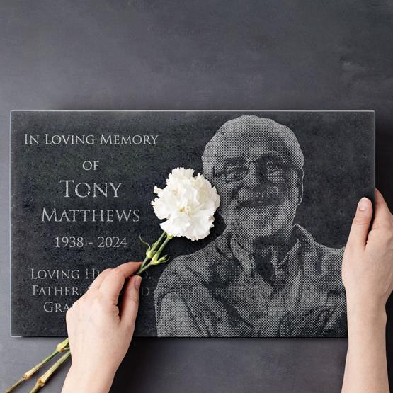 Woman placing a flower on a Custom Engraved Granite Headstone for Tony with his picture engraved into the stone.