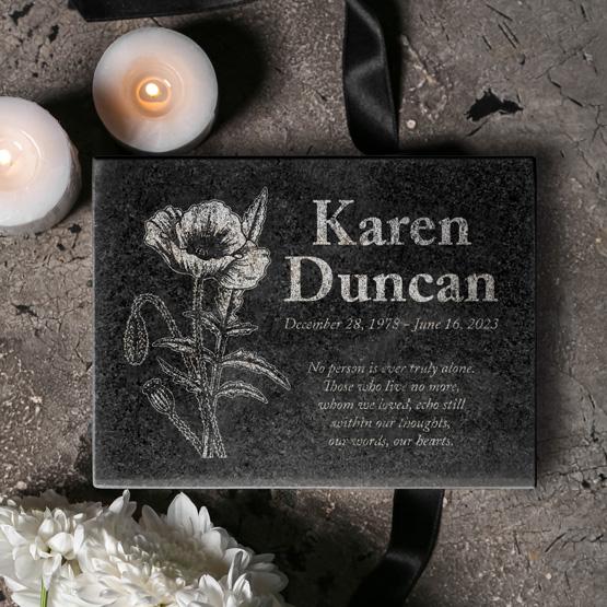 Custom Engraved Granite Urn with Loved One's Name and details. Urn is surrounded by candles and flowers. 