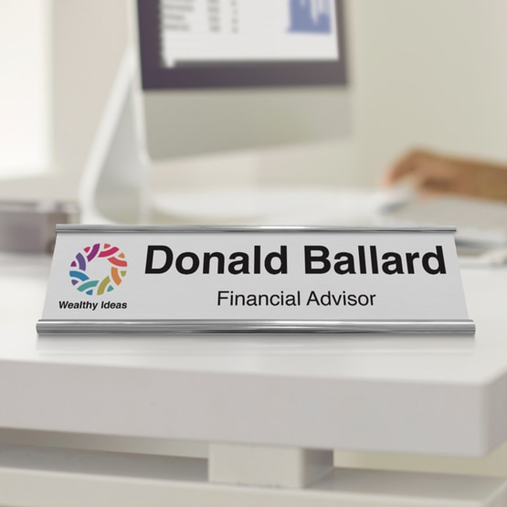 Custom printed aluminum desk name plate for Donald Ballard on edge of white desk.