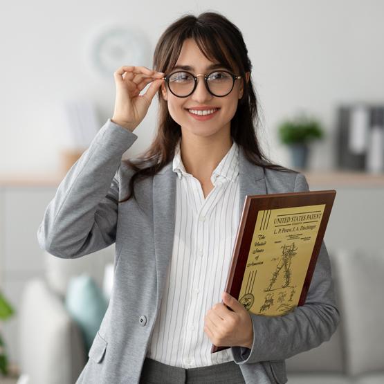 Smart and Happy Woman holding a Custom Patent Plaque with Gold Metal and Coated Cherry Board.