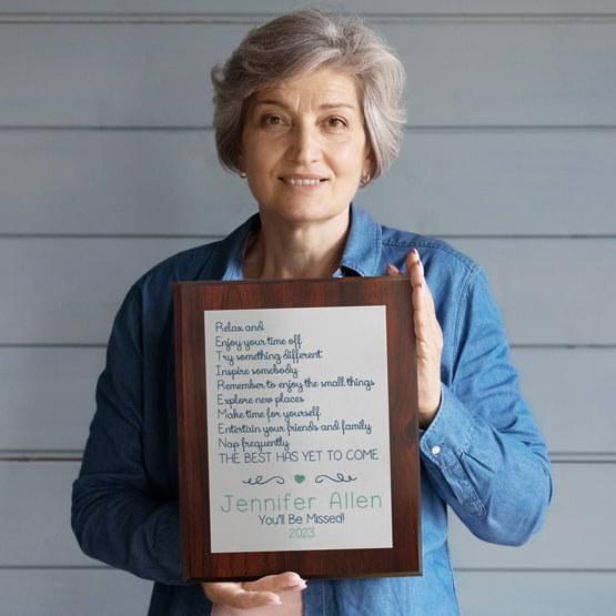 Old Woman With Gray Hair Holding Retirement Plaque Gift With Silver Plate And Custom Acronym Message And Cherry Board