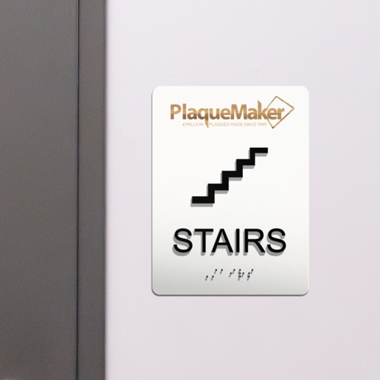 ADA office door signs with tactile lettering and Grade 2 braille hanging by a door.
